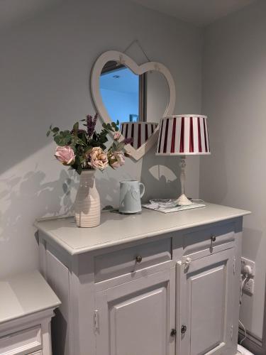a dressing table with a lamp and a mirror at Lilac Terrace Cottage in Danby