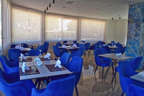 uma sala de jantar com cadeiras e mesas azuis em corail royal hotel em Tabarka