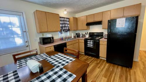 cocina con mesa y nevera negra en The Blue Door at Sylva Home Base Apartments, en Sylva