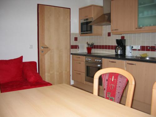a kitchen with a wooden table and a red chair at Hansalagut in Mauterndorf