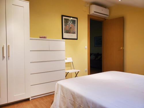 a bedroom with a white bed and a dresser at El Ático in Tordesillas