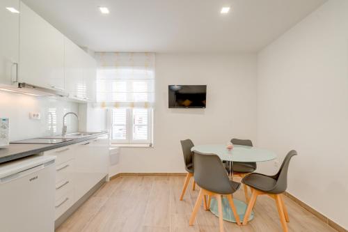 cocina blanca con mesa y sillas en Apartments Villa Tudor 1, en Hvar