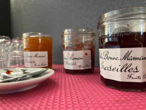 two jars of jam on a table with a plate of food at Hôtel Le Lacuzon in Moirans-en-Montagne