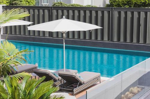 an umbrella and chairs next to a swimming pool at Hotel Marina Atlântico in Ponta Delgada