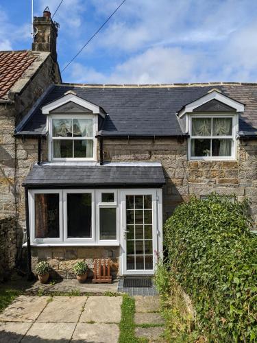 a stone house with a white door and windows at Lilac Terrace Cottage in Danby