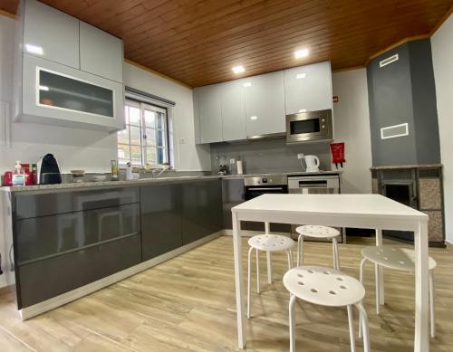 uma cozinha com uma mesa branca e dois bancos em Casinha da Ti'Augusta em Lamego