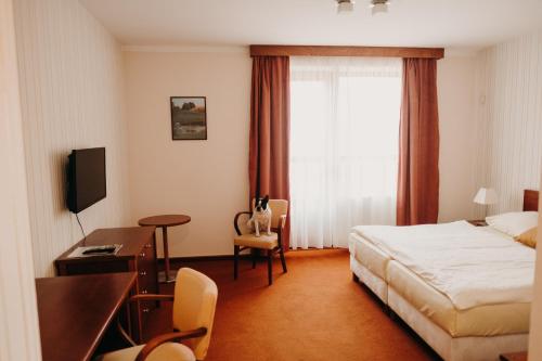 Habitación de hotel con cama, escritorio y ventana en Golf Hotel Austerlitz en Slavkov u Brna