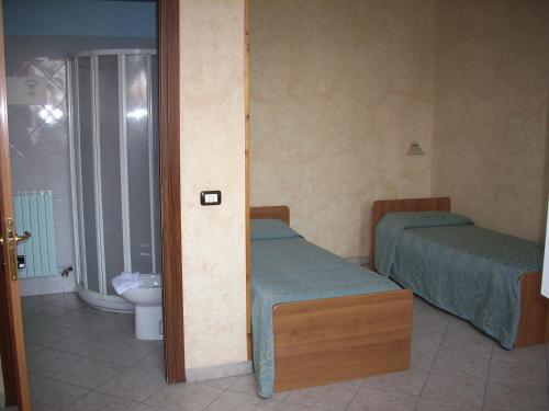 a room with two beds and a bathroom with a toilet at Il Bivio Hotel in Carmagnola