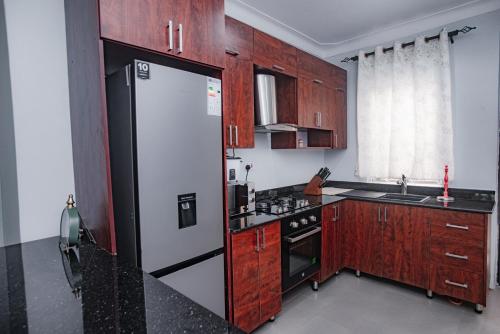 a kitchen with wooden cabinets and a black and white refrigerator at PearlCrest townhomes in Kampala