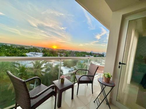 a balcony with chairs and a view of a sunset at Cozy Hideaway Apt Near Beach in Boca Chica