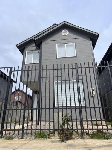 a house behind a fence in front at Casa Nueva 3 dormitorios 2B in Puerto Montt