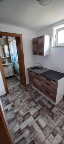 cocina con armarios de madera y suelo de baldosa en SOBE ROOMS GAVRILO, en Banja Luka