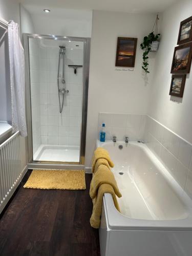 ein Bad mit einer Badewanne und einer Dusche mit einem Handtuch in der Unterkunft Brownrigg in Otterburn