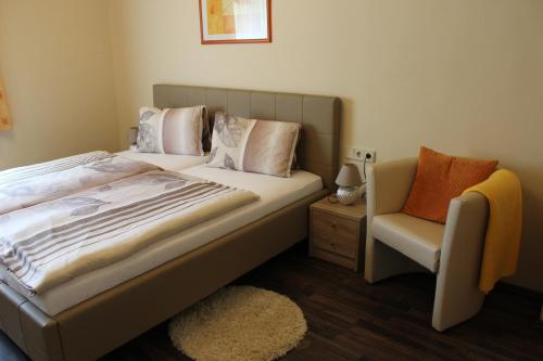 a bedroom with a large bed and a chair at Gasthof Pension Jägerwirt in Velden am Wörthersee