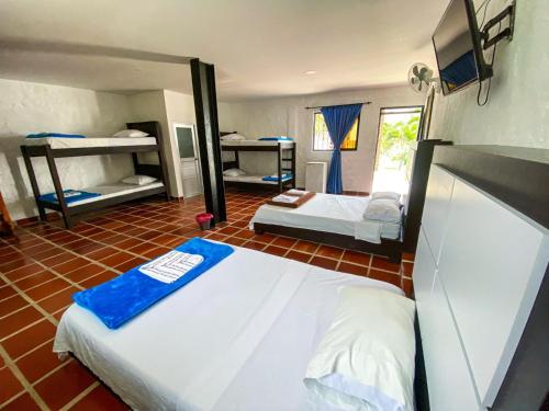 a bedroom with two beds and a tv in it at Hotel Campestre La María Toro Valle in Toro