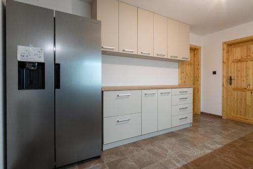 a kitchen with a stainless steel refrigerator and white cabinets at Rezidencia Podhájska in Podhájska