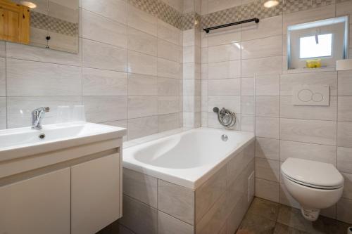a bathroom with a tub and a toilet and a sink at Rezidencia Podhájska in Podhájska