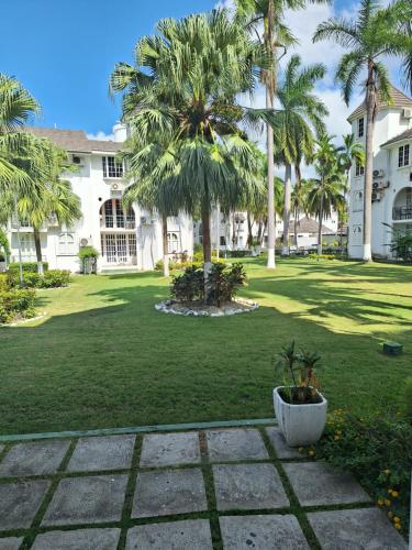 a large yard with palm trees and a building at Beach One Bedroom 2 in Ocho Rios