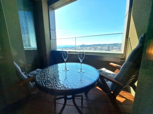 two wine glasses sitting on a table in front of a window at Prestigious SKY PARK apartment - top city view - Traveller awards 2024 in Bratislava