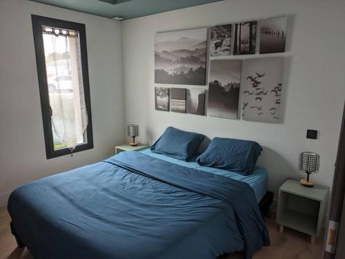 een slaapkamer met een blauw bed en 2 ramen bij Rez de jardin proche de la mer in Arradon