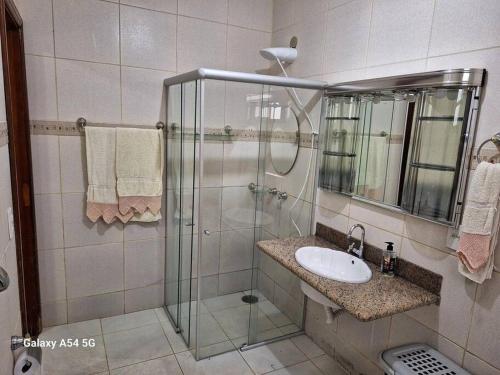 uma casa de banho com uma cabina de duche em vidro e um lavatório. em Casa de temporada Uberaba piscina em Uberaba