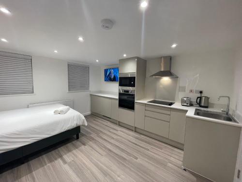 a white kitchen with a bed and a sink at Riverside Studio Apartment Docklands E14 in London