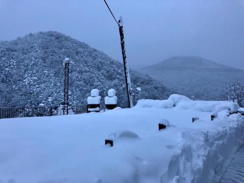 a pile of snow next to two chairs and a mountain at Apartamentos Zabalarena Basoa in Orbaiceta