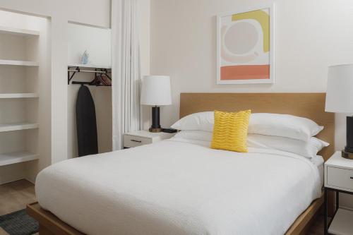 a bedroom with a white bed with a yellow pillow at WaterWalk Extended Stay by Wyndham Huntsville in Huntsville