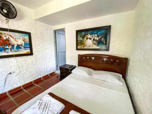 a bedroom with a bed and paintings on the wall at Hotel Campestre La María Toro Valle in Toro