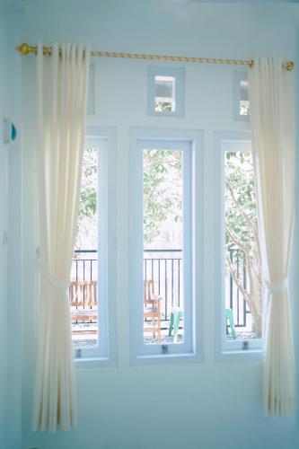 a window with curtains in a room with a balcony at Getrudis Guesthouse in Labuan Bajo