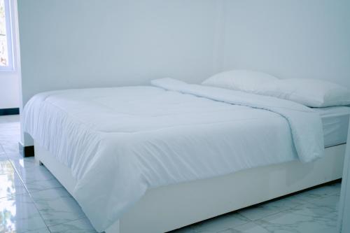 Cama blanca con sábanas y almohadas blancas en Getrudis Guesthouse en Labuan Bajo