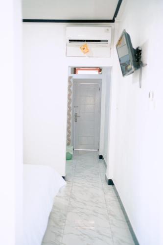 a hallway with white walls and a white door at Getrudis Guesthouse in Labuan Bajo