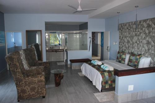 a bedroom with a bed and a couch and a chair at Ecolux in Marracuene