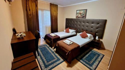 a hotel room with two beds and a table at Hanul Lui Bogdan Economy INN in Făget