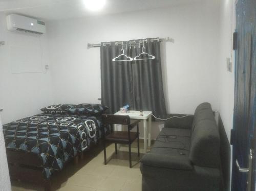 a bedroom with a bed and a couch and a table at chinaka guest house 24hr light in Lagos