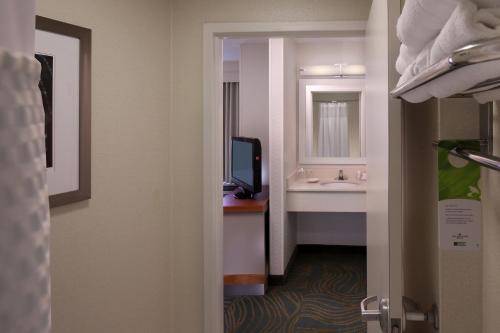 a room with a bathroom with a sink and a tv at SpringHill Suites by Marriott Waterford / Mystic in New London