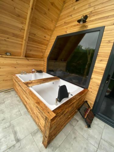 a bath tub in a wooden room with a large window at Sıcak havuzlu dağ evi in Sapanca