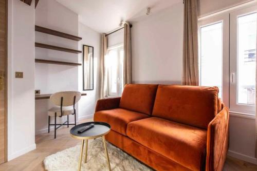 sala de estar con sofá naranja y taburete en Lovely studio - Pigalle Moulin Rouge, en París