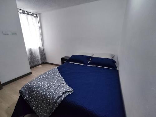a bedroom with a bed with blue sheets and a window at Apartamento con piscina, frente a CC Mayorca in Sabaneta