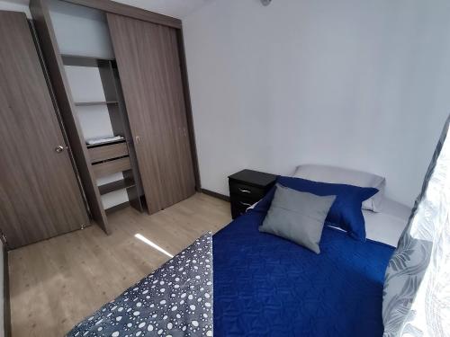 a bedroom with a bed with blue sheets and pillows at Apartamento con piscina, frente a CC Mayorca in Sabaneta