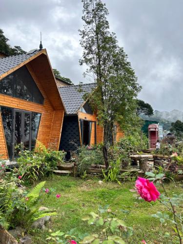 a wooden house with a garden in front of it at Mando Homestay in Bắc Yên