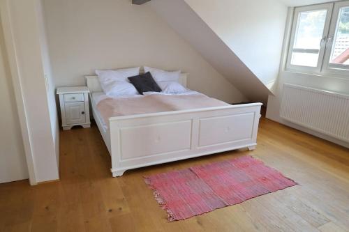 Cama blanca en habitación con alfombra roja en Ferienwohnung Heimbach Burgblick, en Heimbach