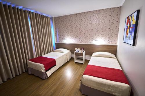 a hotel room with two beds and a window at Foz Plaza Hotel in Foz do Iguaçu