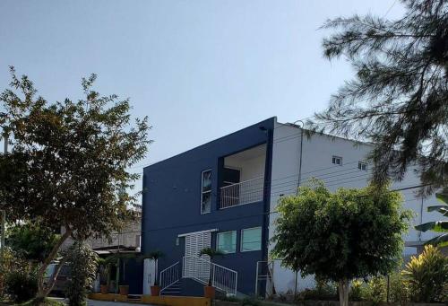ein blau-weißes Gebäude mit Bäumen davor in der Unterkunft Lugar perfecto para descansar.²⁰³ in Fortín de las Flores
