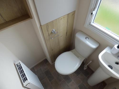 a small bathroom with a toilet and a sink at Orchards 29 at Southview Leisure Park in Skegness
