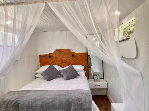 1 dormitorio con 1 cama grande y cortinas blancas en NoZaDi classic horse trailer converted into a unique tiny home, 
