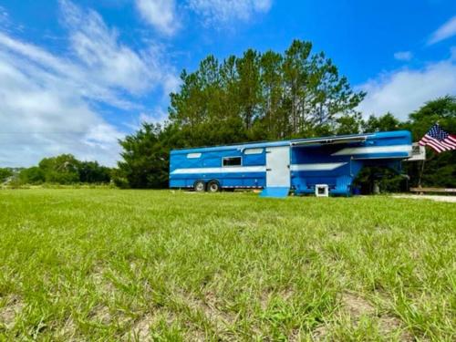 un autobús azul estacionado en un campo de césped en NoZaDi classic horse trailer converted into a unique tiny home, 