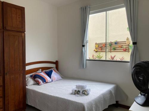 a small bedroom with a bed with a window at Casa Brisas Arembepe - arejada e aconchegante - litoral norte da Bahia - WiFi in Arembepe