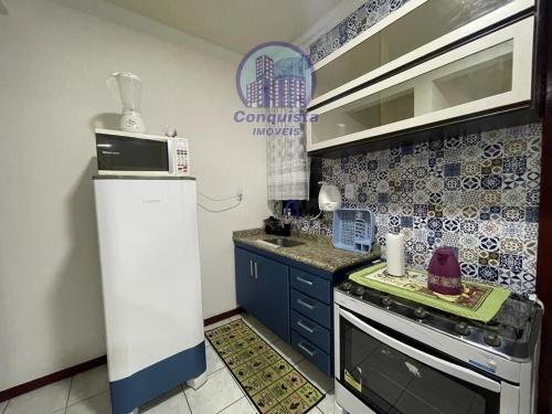 a small kitchen with a refrigerator and a stove at Apto Conquista Imóveis exclusivo para Booking in Vitória da Conquista