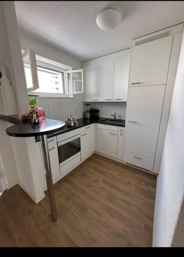 une cuisine avec des placards blancs et une table. dans l'établissement Yigits Rooms, à Lucerne